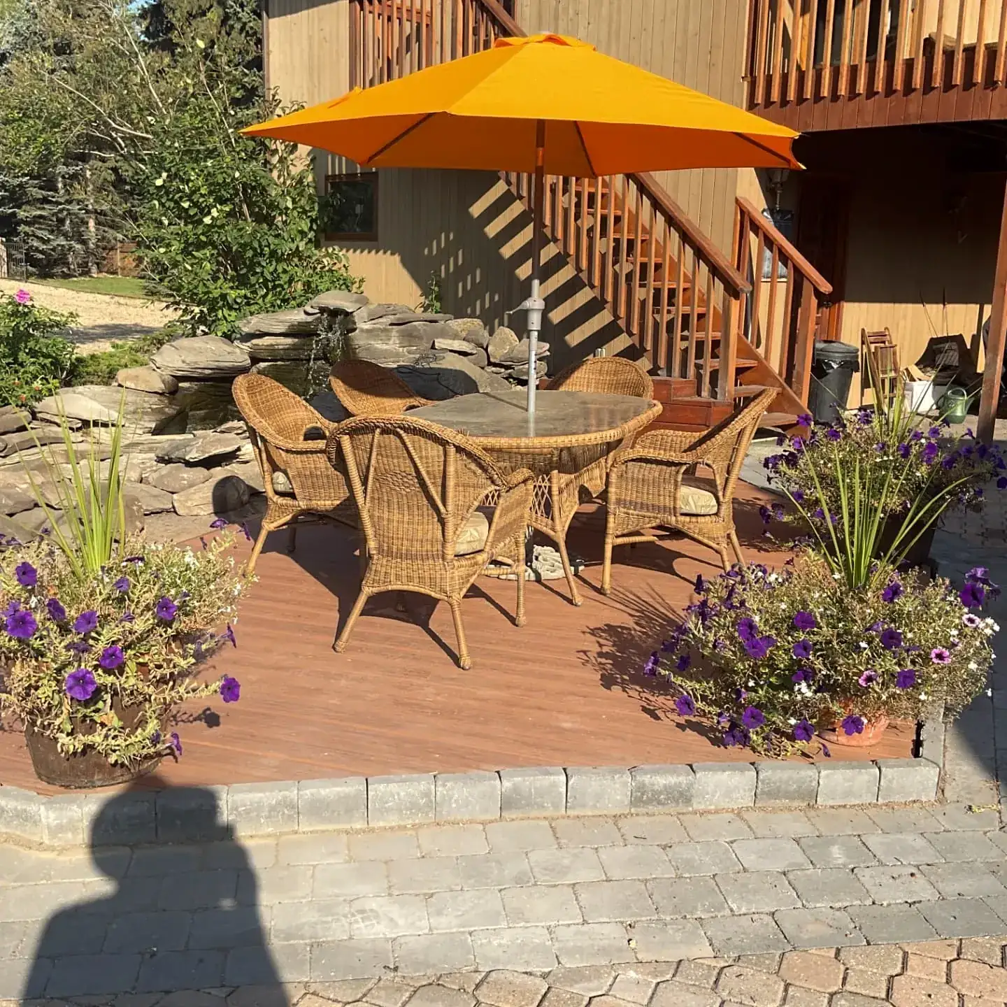 Trex deck in stone landscaping with an orange umbrella