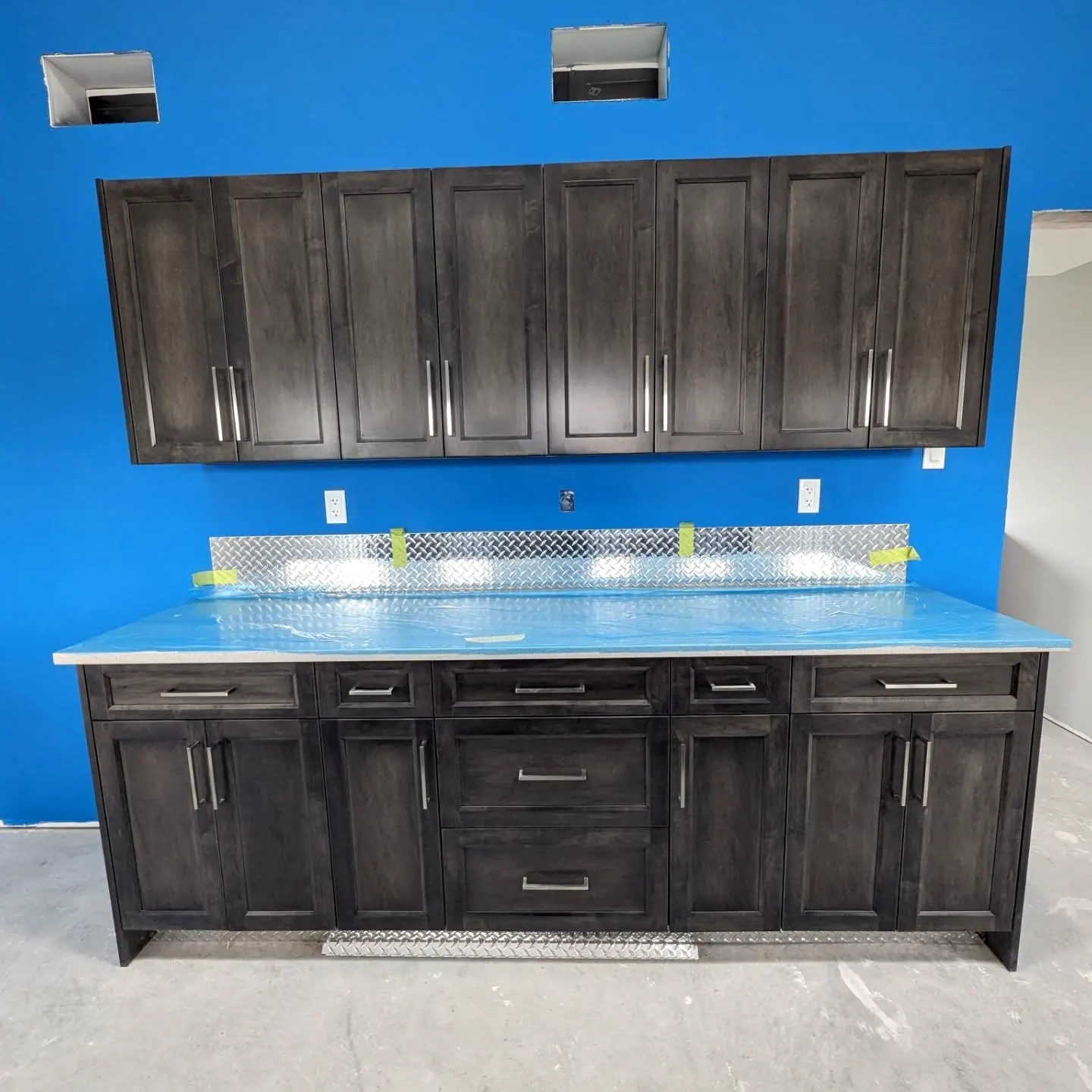 Dark stained upper and lower cabinets on a blue wall