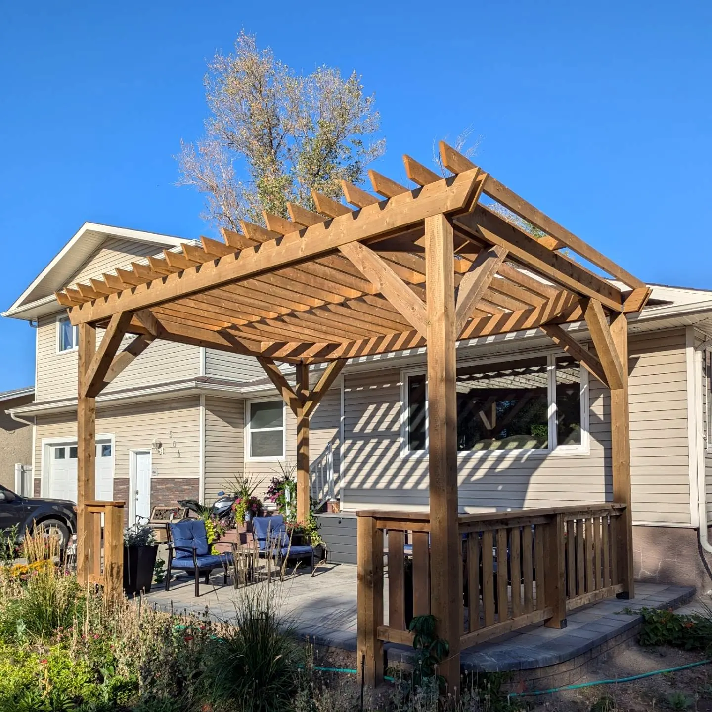 Timber pergola over a paver patio, railings at the corners