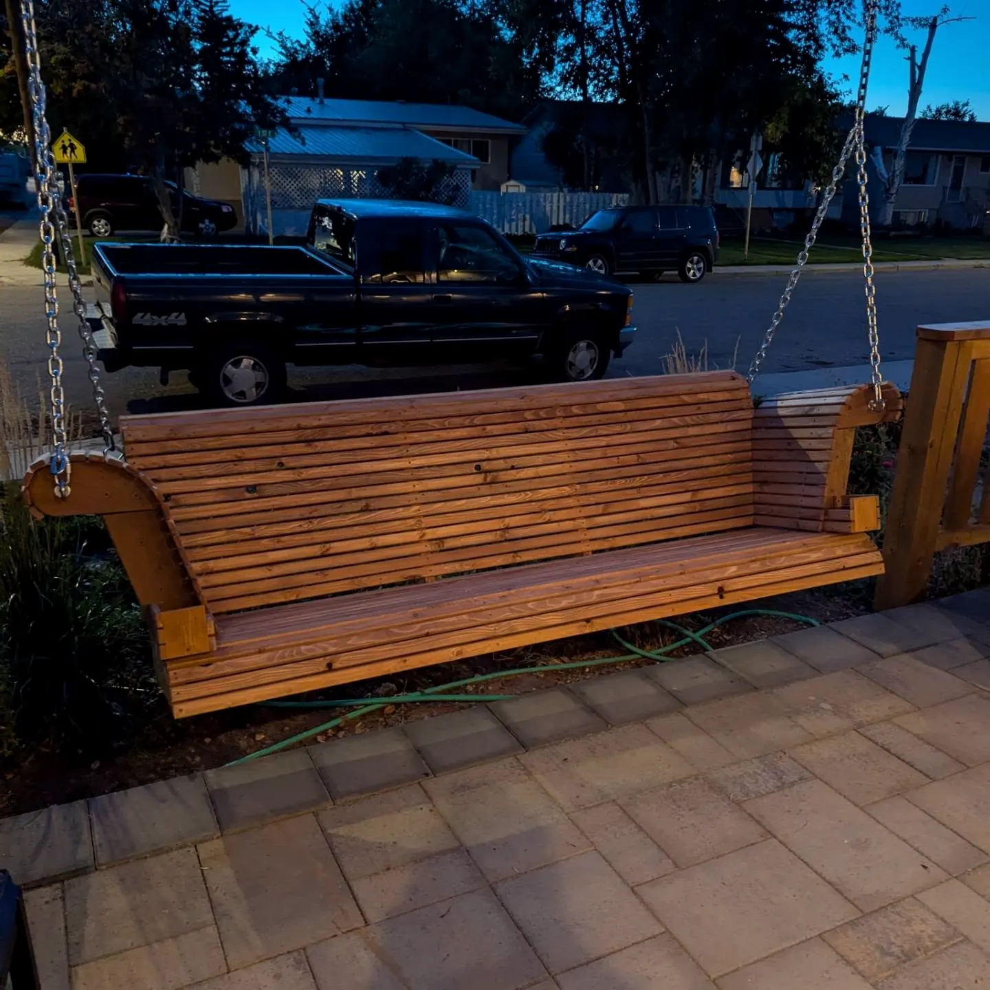 Wood bench swing hanging from the pergola on chains