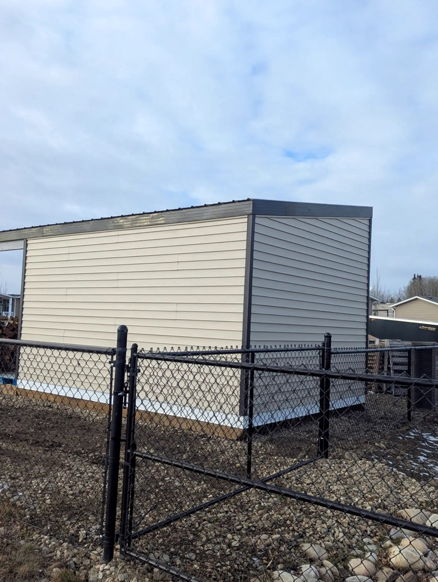 Sided outbuilding behind a chain-link fence
